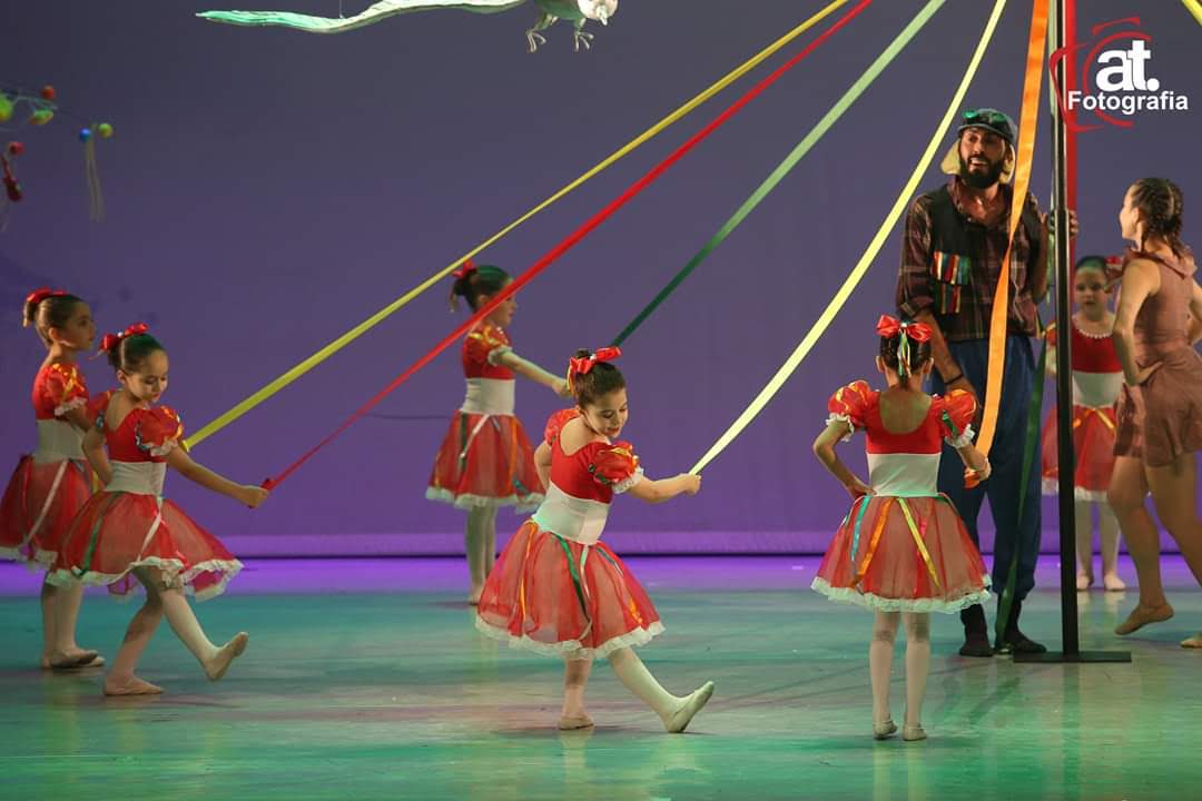Crianças dançando com fitas coloridas no palco